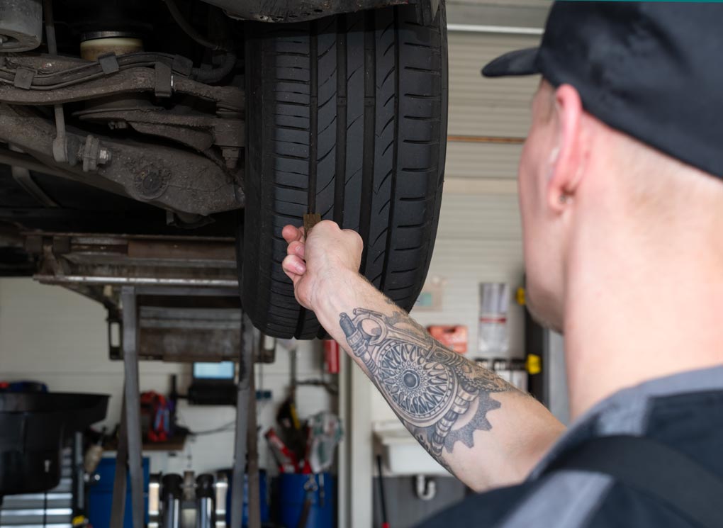 Automechaniker prüft Reifenprofil